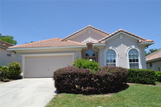mediterranean / spanish home featuring concrete driveway, a tiled roof, an attached garage, and stucco siding