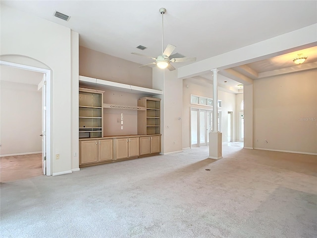 unfurnished living room featuring ceiling fan, decorative columns, light colored carpet, and visible vents