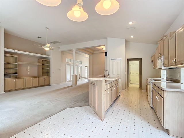 kitchen featuring ceiling fan, a center island with sink, a sink, light countertops, and white appliances