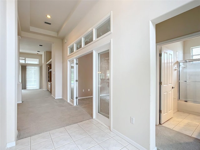 corridor featuring light tile patterned flooring, light colored carpet, french doors, and visible vents