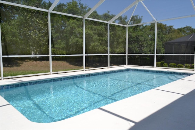 outdoor pool with glass enclosure and a patio area