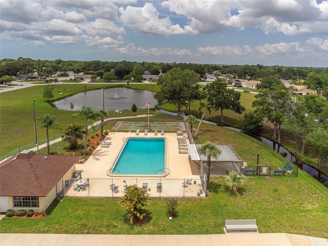 pool with fence, a water view, and a yard