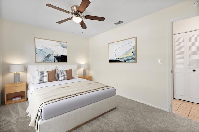 carpeted bedroom featuring baseboards, ceiling fan, tile patterned flooring, and visible vents