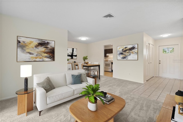 living area with visible vents, baseboards, light tile patterned floors, and light colored carpet