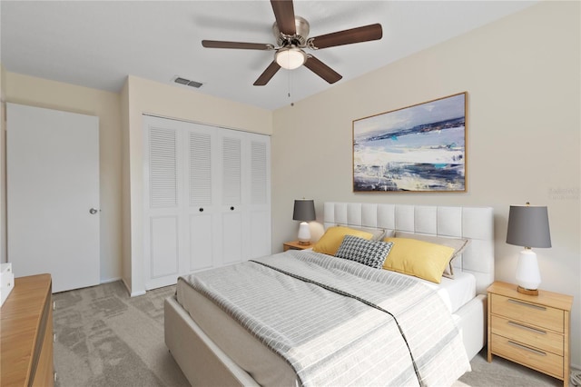 bedroom featuring visible vents, a closet, ceiling fan, and light colored carpet