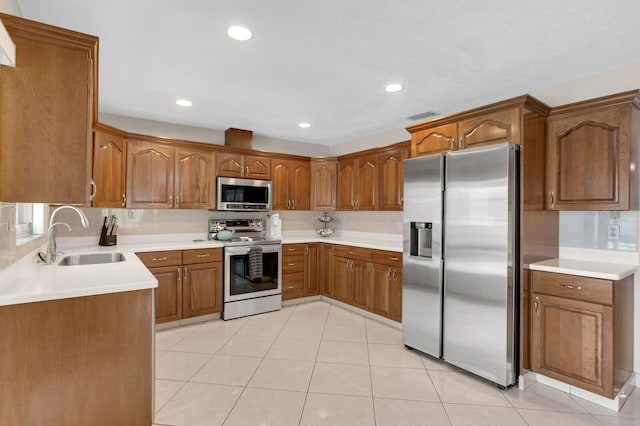 1403 Garden Ave, Tarpon Springs, FL 34689 - kitchen featuring stainless steel appliances, a sink, brown cabinetry, light tile patterned floors, and light countertops