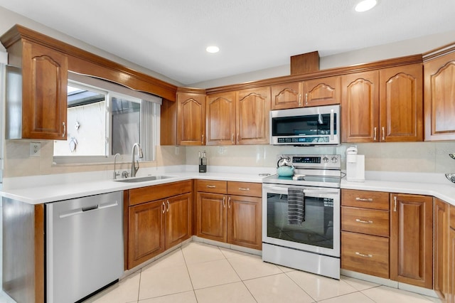1403 Garden Ave, Tarpon Springs, FL 34689 - kitchen featuring appliances with stainless steel finishes, a sink, brown cabinetry, light tile patterned floors, and recessed lighting