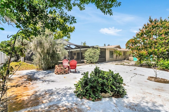 1403 Garden Ave, Tarpon Springs, FL 34689 - back of house featuring glass enclosure, an outdoor fire pit, a patio area, and stucco siding