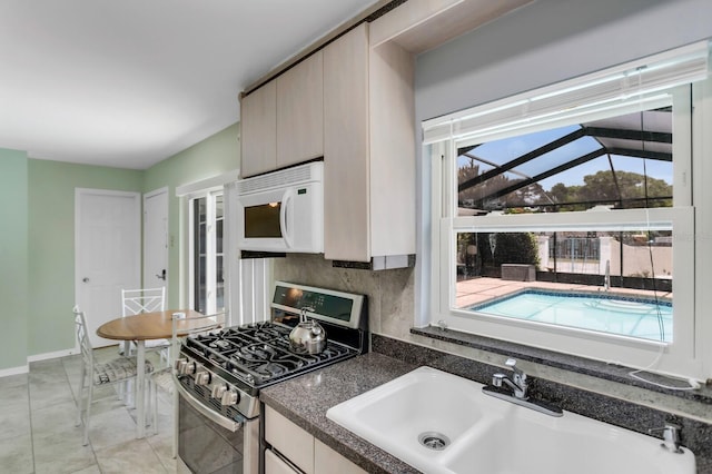 1403 Garden Ave, Tarpon Springs, FL 34689 - kitchen featuring stainless steel gas stove, white microwave, a sink, dark countertops, and baseboards