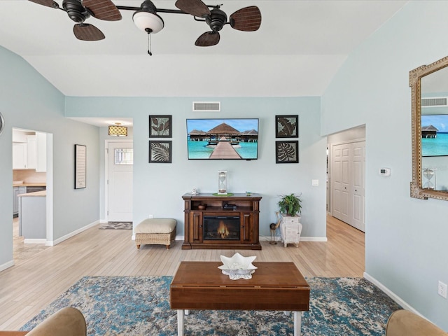 living area featuring ceiling fan, light wood finished floors, visible vents, and lofted ceiling
