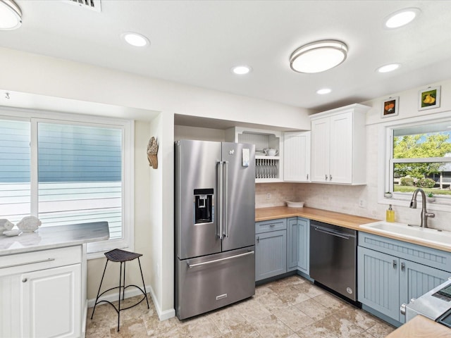 kitchen with white cabinets, open shelves, appliances with stainless steel finishes, a sink, and backsplash