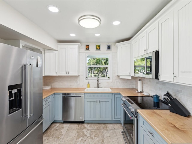 kitchen with stainless steel appliances, wood counters, plenty of natural light, and a sink