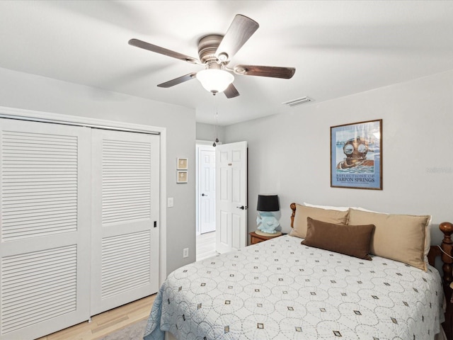 bedroom featuring visible vents, light wood finished floors, ceiling fan, and a closet