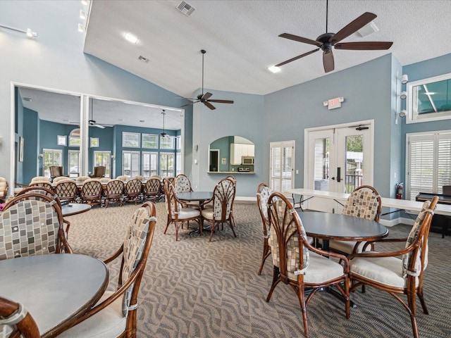 carpeted dining space with visible vents, ceiling fan, high vaulted ceiling, a textured ceiling, and french doors