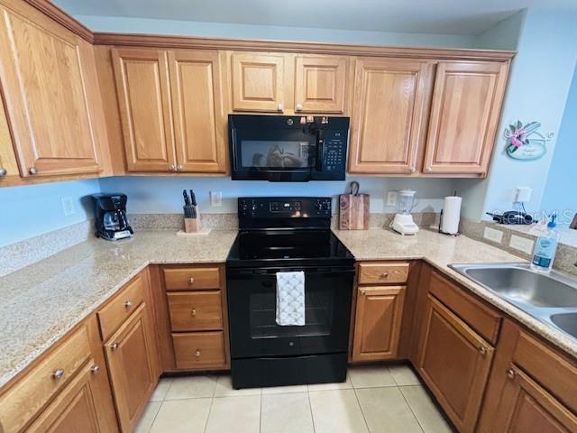 13415 Blue Heron Beach Dr Unit 1006, Orlando, FL 32821 - kitchen with light stone countertops, a sink, light tile patterned floors, and black appliances
