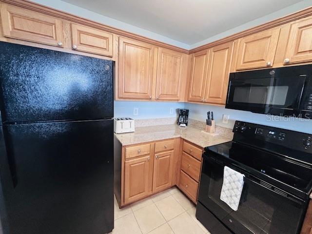13415 Blue Heron Beach Dr Unit 1006, Orlando, FL 32821 - kitchen with light countertops, light tile patterned floors, light brown cabinetry, and black appliances