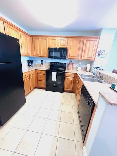 13415 Blue Heron Beach Dr Unit 1006, Orlando, FL 32821 - kitchen with a sink, a peninsula, light tile patterned flooring, and black appliances