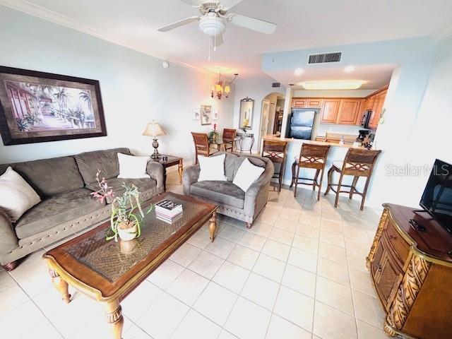 13415 Blue Heron Beach Dr Unit 1006, Orlando, FL 32821 - living area with arched walkways, visible vents, light tile patterned floors, and ceiling fan with notable chandelier