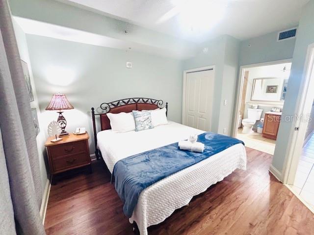 13415 Blue Heron Beach Dr Unit 1006, Orlando, FL 32821 - bedroom featuring visible vents, connected bathroom, wood finished floors, and a closet