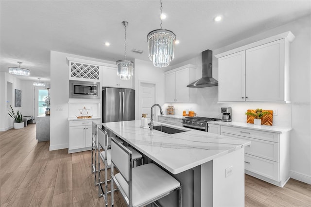 kitchen featuring visible vents, a sink, a chandelier, stainless steel appliances, and wall chimney exhaust hood