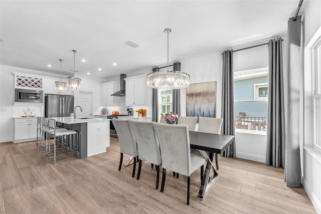 dining area with an inviting chandelier, a healthy amount of sunlight, and light wood-type flooring
