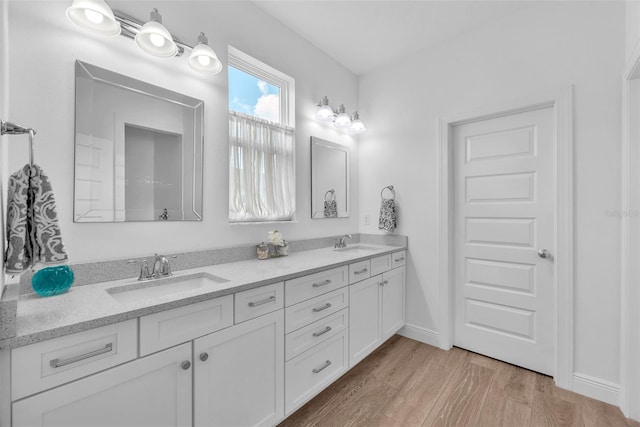 full bath featuring double vanity, a sink, and wood finished floors