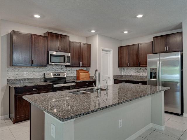 413 Royal Empress Dr, Ruskin, FL 33570 - kitchen featuring appliances with stainless steel finishes, a sink, light tile patterned floors, dark brown cabinets, and dark stone countertops