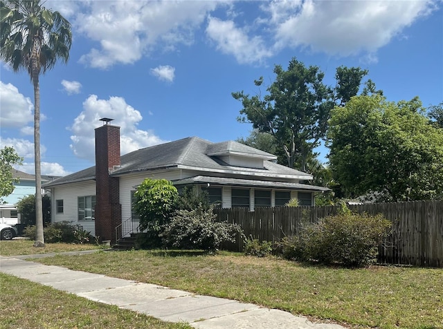 view of home's exterior featuring fence, a yard, and a chimney