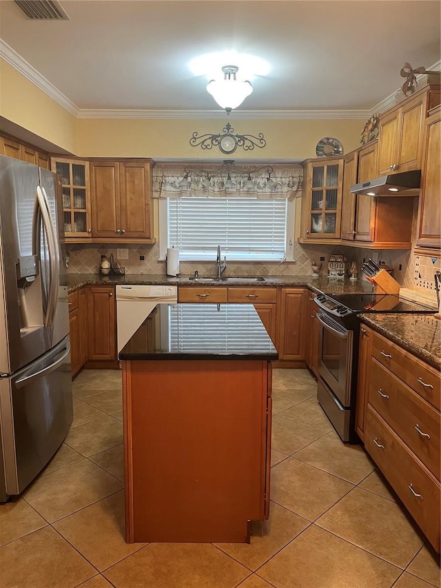 kitchen with light tile patterned flooring, under cabinet range hood, tasteful backsplash, a sink, and appliances with stainless steel finishes
