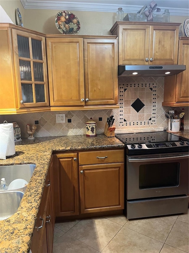kitchen with electric stove, backsplash, stone counters, light tile patterned floors, and under cabinet range hood