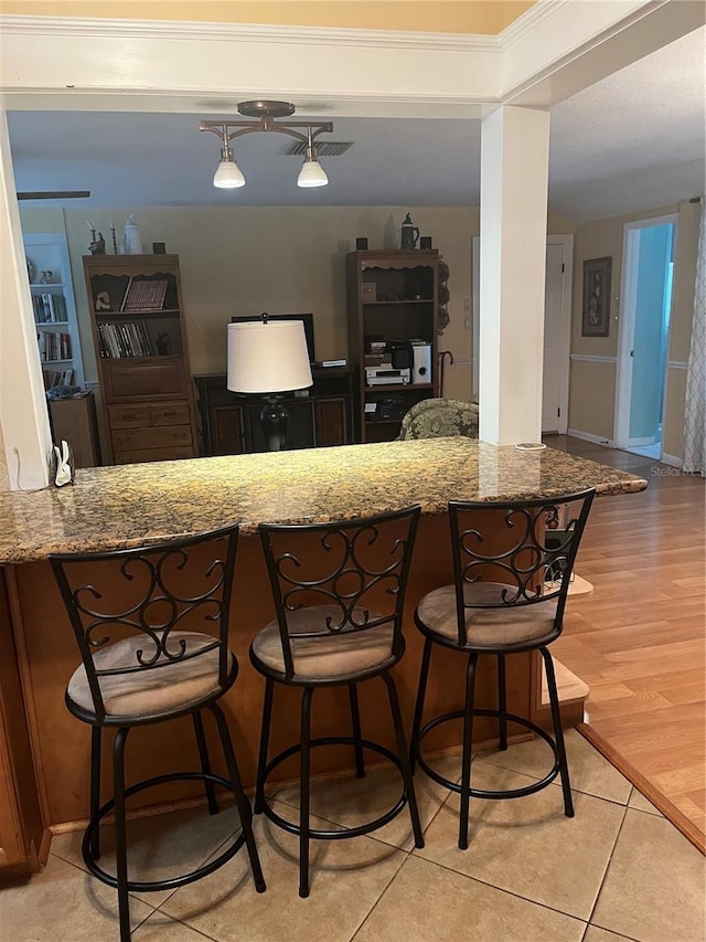 kitchen with stone counters, a breakfast bar, and light wood-type flooring