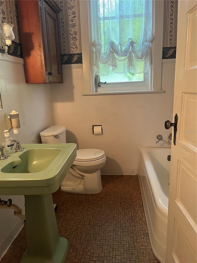 bathroom with a sink, a tub, and toilet