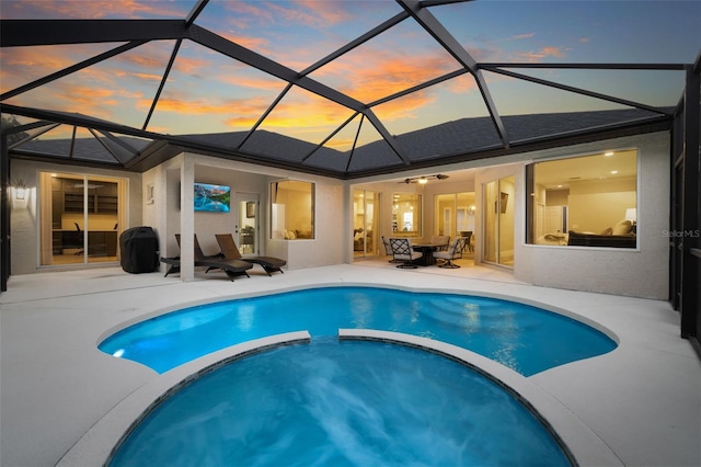 pool at dusk with a patio, a lanai, and a pool with connected hot tub
