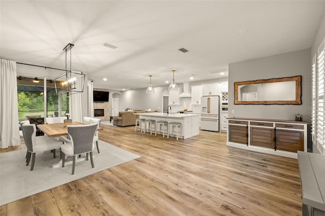 dining room with recessed lighting, visible vents, light wood finished floors, and a fireplace