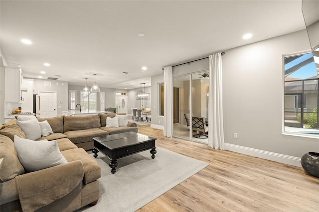living room featuring light wood-type flooring, recessed lighting, baseboards, and a healthy amount of sunlight
