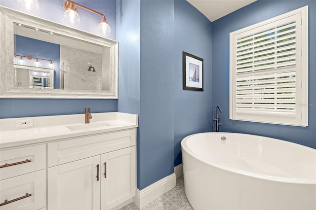 full bath featuring a freestanding bath, baseboards, vanity, and tile patterned floors