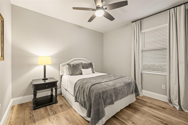 bedroom with light wood-type flooring, a ceiling fan, and baseboards