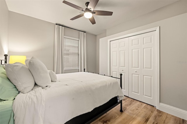 bedroom featuring baseboards, light wood-style flooring, ceiling fan, and a closet