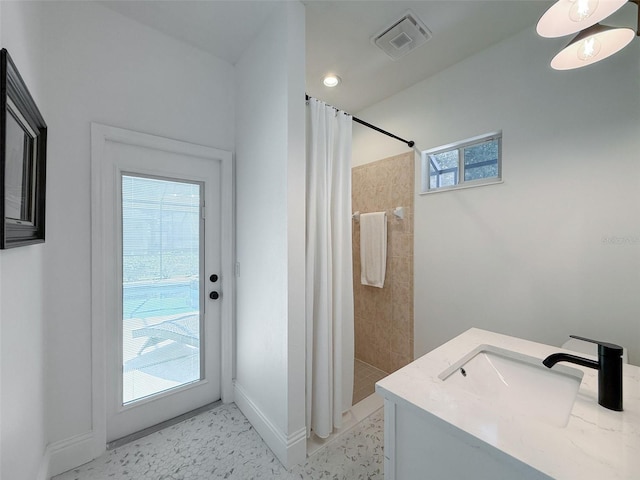 full bath with tiled shower, baseboards, visible vents, and a sink