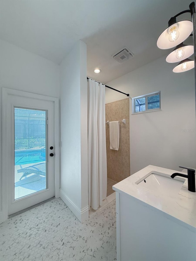 full bath featuring visible vents, a sink, baseboards, and tiled shower