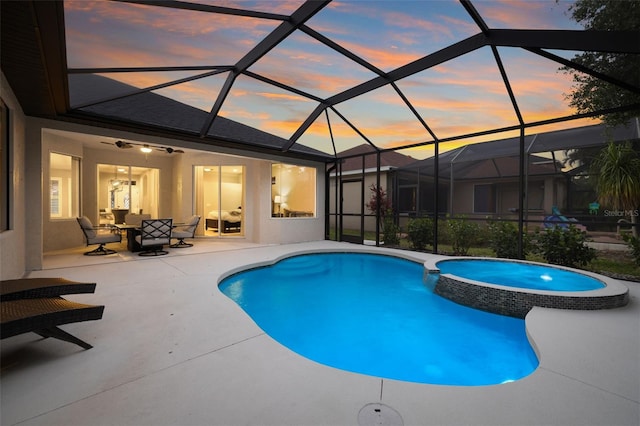 view of swimming pool with a ceiling fan, glass enclosure, a patio area, and a pool with connected hot tub