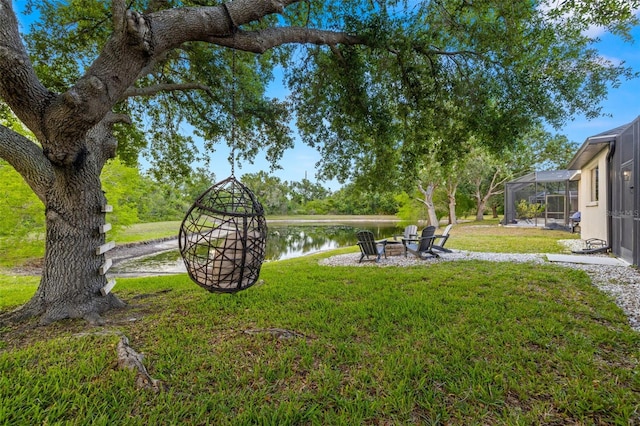 view of yard with a lanai, a water view, and a fire pit