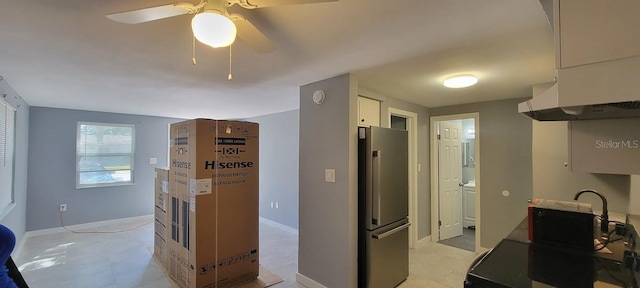 kitchen with freestanding refrigerator, a ceiling fan, white cabinets, and baseboards