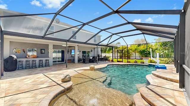 outdoor pool featuring a patio, glass enclosure, and outdoor dry bar