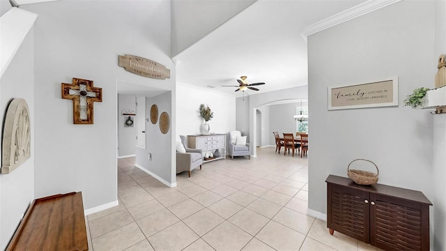 entrance foyer featuring baseboards, arched walkways, a ceiling fan, and light tile patterned floors
