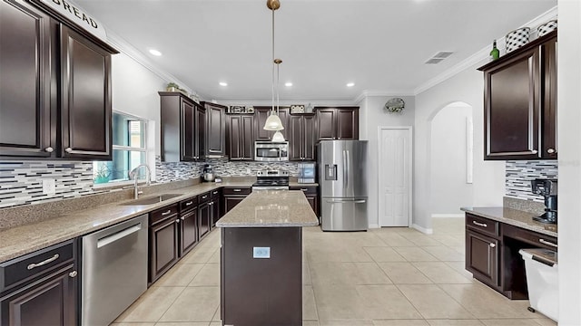 kitchen featuring crown molding, visible vents, arched walkways, a sink, and appliances with stainless steel finishes