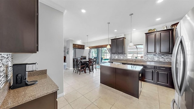 kitchen with freestanding refrigerator, backsplash, ornamental molding, and a sink