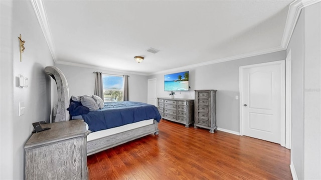 bedroom with crown molding, baseboards, wood finished floors, and visible vents