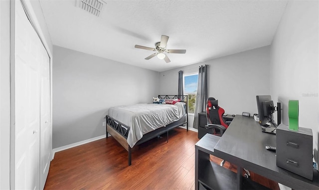 bedroom featuring visible vents, a closet, wood finished floors, baseboards, and a ceiling fan