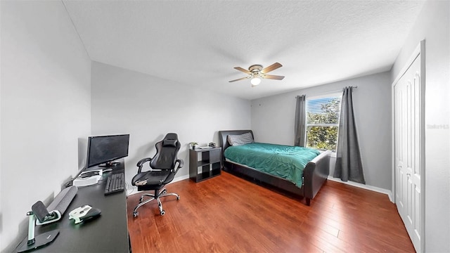 bedroom featuring baseboards, a textured ceiling, ceiling fan, and wood finished floors